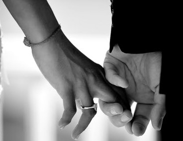Close up of bride and groom holding hands in black and white